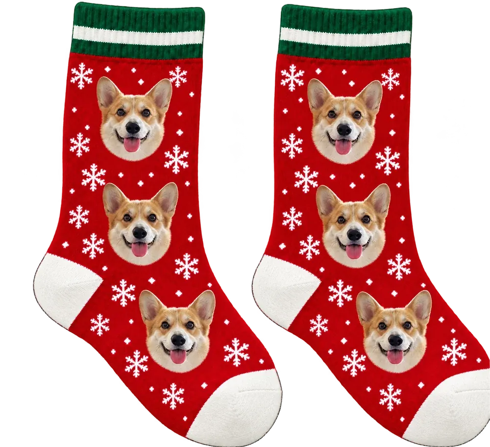 Red snowflake crew socks with green-and-white cuffs, printed with a corgi’s face, three on each sock