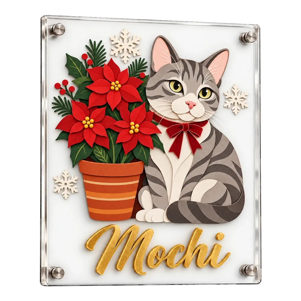 A clear acrylic plaque with a grey tabby in a red velvet bow beside red poinsettias, built up in layers of cut glass, and Mochi in raised gold script